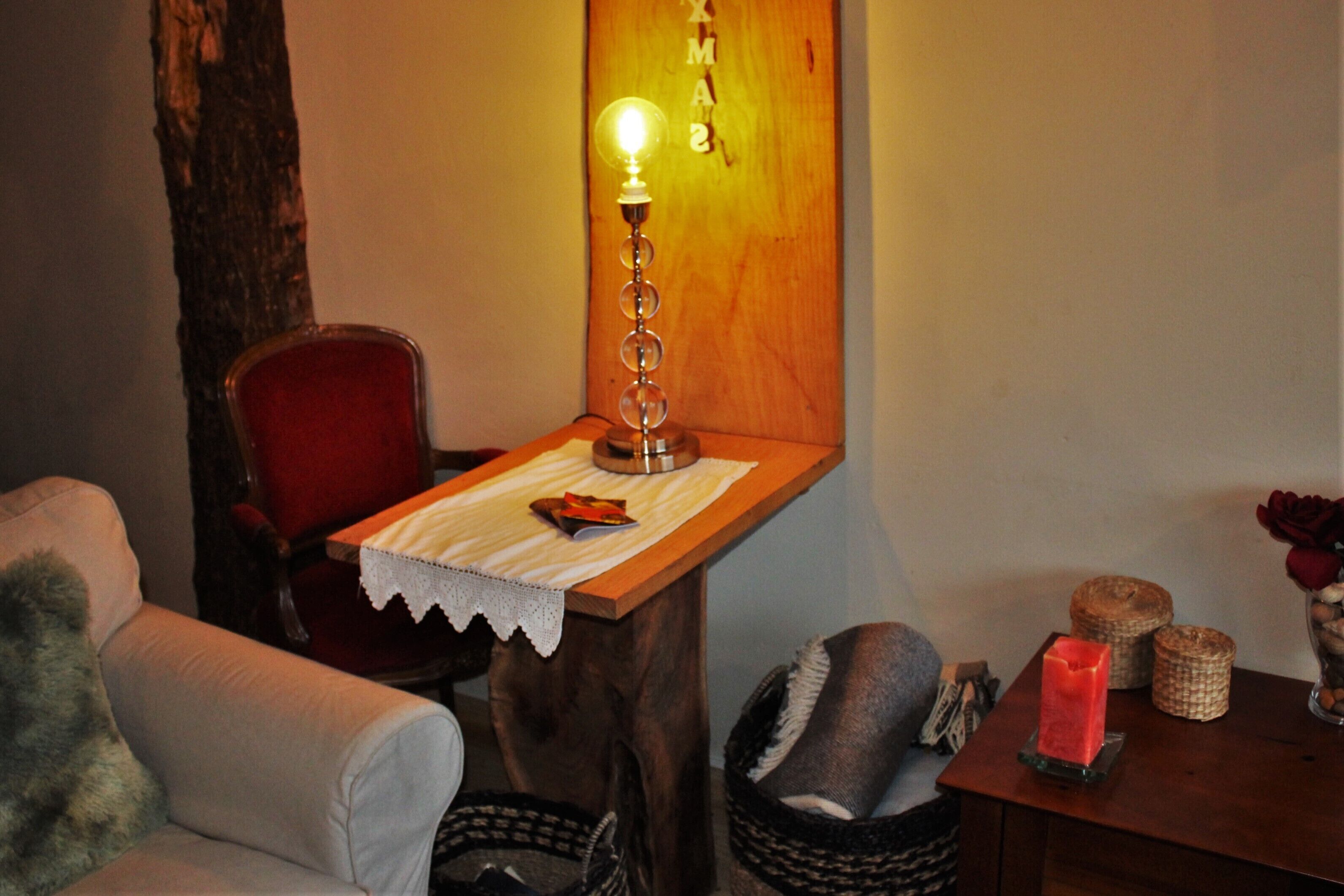 Un rincón acogedor con una mesa de madera, una silla roja, una lámpara y una cesta.