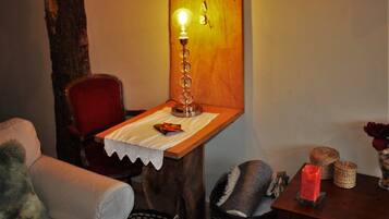 Un rincón acogedor con una mesa de madera, una silla roja, una lámpara y una cesta.