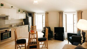 Een modern appartement met keuken, eetgedeelte, woonkamer en een televisie.