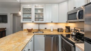 Una cocina moderna con armarios blancos, encimera de granito, electrodomésticos de acero inoxidable y lavavajillas.