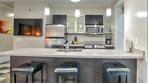 Una cocina moderna con electrodomésticos de acero inoxidable, una isla grande con taburetes de bar e iluminación colgante.