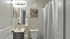 Un baño con inodoro, lavamanos, espejo y cortina de ducha.