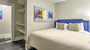 Un dormitorio con cama, ventilador de techo, un cuadro y estanterías empotradas.