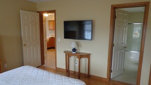 Een slaapkamer met een bed, een televisie en een deur naar een badkamer.