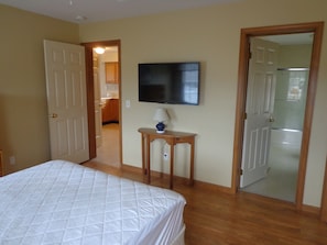 Une chambre à coucher comprenant un lit, un téléviseur et une porte donnant sur une salle de bain.