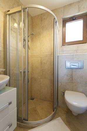 A bathroom with a glass-enclosed shower, a toilet, and a sink. - Beautiful 2 Bed, 2 Bath apartment with sea views, shared large, salt water pools (Kalkan)