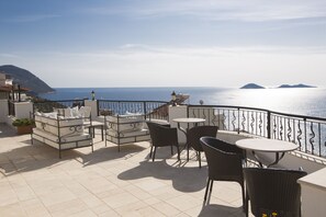 A terrace with a sofa, chairs, and a table overlooking the sea. - Beautiful 2 Bed, 2 Bath apartment with sea views, shared large, salt water pools (Kalkan)