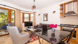 Ein modernes Wohnzimmer mit einer Couch, einem Esstisch und einer Küchenzeile mit einem Herd.