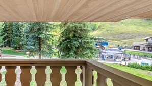Ein Balkon mit Blick auf einen Park, Bäume und ein entferntes Gebäude.