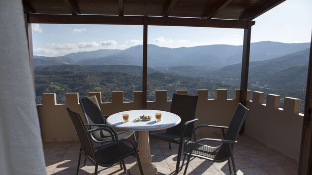 Une terrasse avec une table ronde et quatre chaises, offrant une vue sur un paysage montagneux.