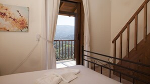 Une chambre avec un lit, un tableau, un balcon et une vue sur les montagnes.