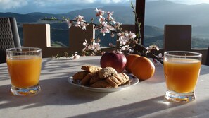 Ein Tisch mit zwei Gläsern Orangensaft, einem Teller Keksen, einem Apfel und einem Blumenzweig.