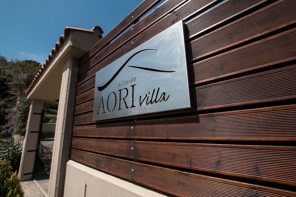 A sign for AORI Villas with a modern design and a wooden facade.