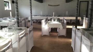 A banquet hall with tables set for a wedding reception, featuring white tablecloths and chairs, and a banner reading "JUST MARRIED".