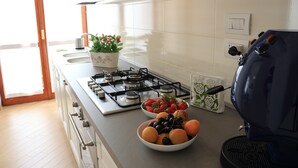 A kitchen with a gas stove, a bowl of fruit, and a coffee maker. - Holiday ABOUT THEATRE (Matera)