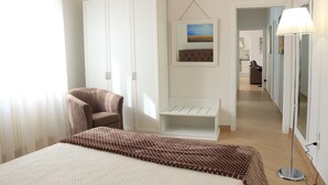 A hotel room with a bed, a wardrobe, a chair, a bedside table, a lamp, and a painting on the wall. - Holiday ABOUT THEATRE (Matera)