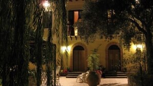 Un patio con un edificio que tiene puertas arqueadas y un balcón.
