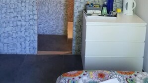 A room with a tiled wall, a white dresser, and a bed with a colorful bedspread. - K.N.C.1601 (La Croix-Valmer)