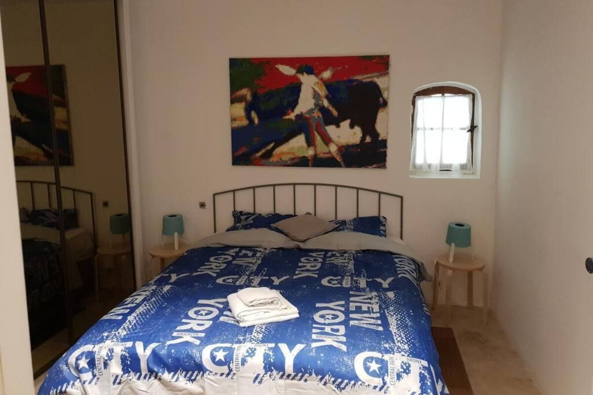 Ein Schlafzimmer mit Bett, einem Gemälde, einem Fenster und einem Spiegel.