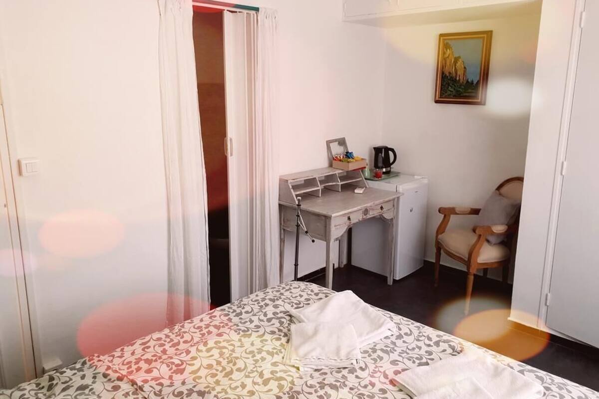Ein kleines, gut beleuchtetes Schlafzimmer mit Bett, Schreibtisch und Stuhl.