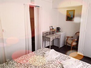 Un dormitorio pequeño y bien iluminado con una cama, un escritorio y una silla.