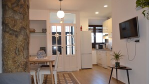 Un espace de vie compact comprenant un coin repas, une kitchenette et un téléviseur fixé au mur.