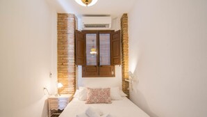 Une petite chambre à coucher accueillante, avec un lit, une table de chevet, une lampe et une fenêtre avec des volets.