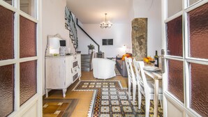 Un salon chaleureux avec un escalier, un coin repas avec une table et des chaises, et un grand élément décoratif mural.