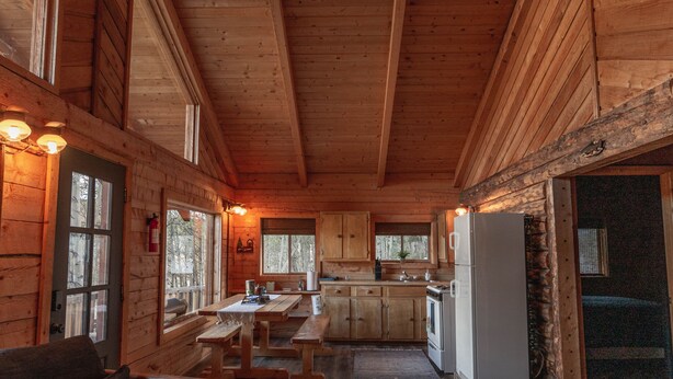 A wooden cabin interior with a dining area, kitchen, and seating. - Technology Free & Dogs are Welcome (Lake City)