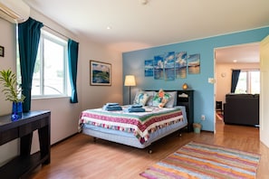 Une chambre à coucher avec un lit, une table de chevet, une lampe et une fenêtre avec des rideaux.
