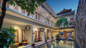 A hotel with a swimming pool, outdoor seating, and a stone wall. - Angkul Angkul Segara Beach Kuta (Kuta)