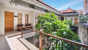 A modern residential building with a balcony, potted plants, and a stone wall. - Angkul Angkul Segara Beach Kuta (Kuta)