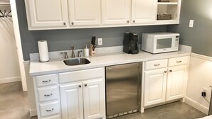 A compact kitchen with white cabinetry, a stainless steel dishwasher, a microwave, and a coffee maker. - The Monticello Guest House - Charming M Streets - Dallas (Dallas)