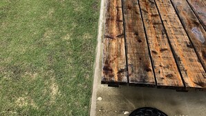 A patio with a wooden table and chairs, a small green table, and a grassy area with plants. - Chakashiya Goten (Onna)