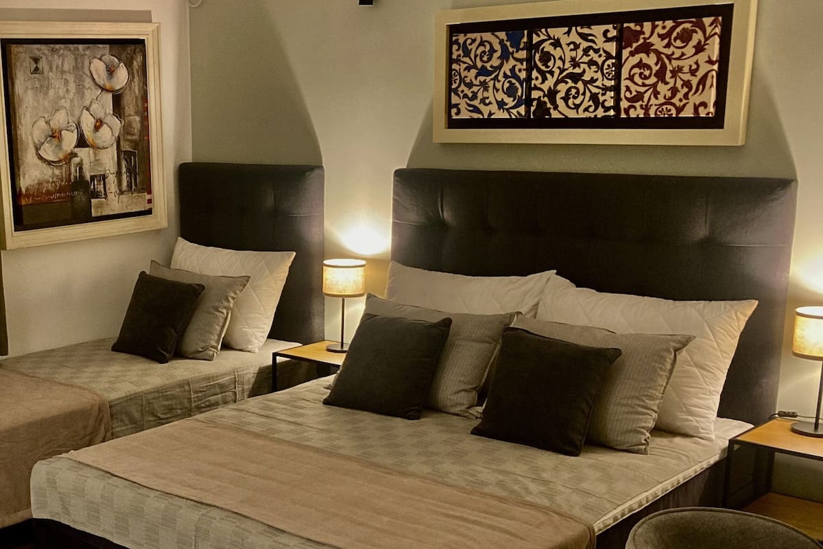 Une chambre d’hôtel avec deux lits, chacun doté d’une tête de lit, de tables de chevet et de lampes.