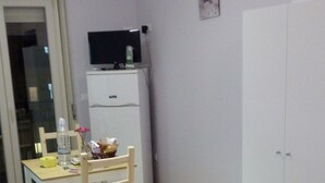 A room with a bed, a desk with a chair, a TV, and a wardrobe. - Lilla'S House Apartment (Caltanissetta)