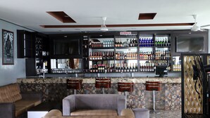 A bar area with multiple shelves of bottles, a non-smoking sign, and a seating area with cushioned chairs. - Crystal Palace Hotel (Abuja)
