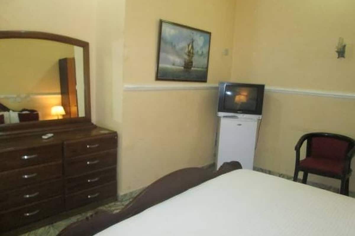 A hotel room with a bed, a dresser, a television, and a chair.