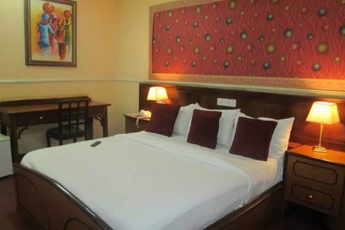A hotel room with a bed, two bedside tables with lamps, a desk, and a chair.
