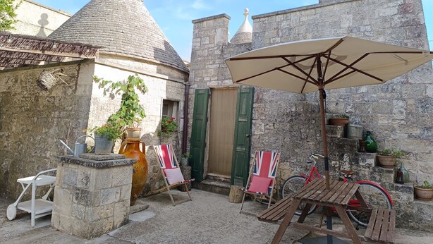 A courtyard with stone buildings, a wooden table, a red bicycle, and a Union Jack flag.
