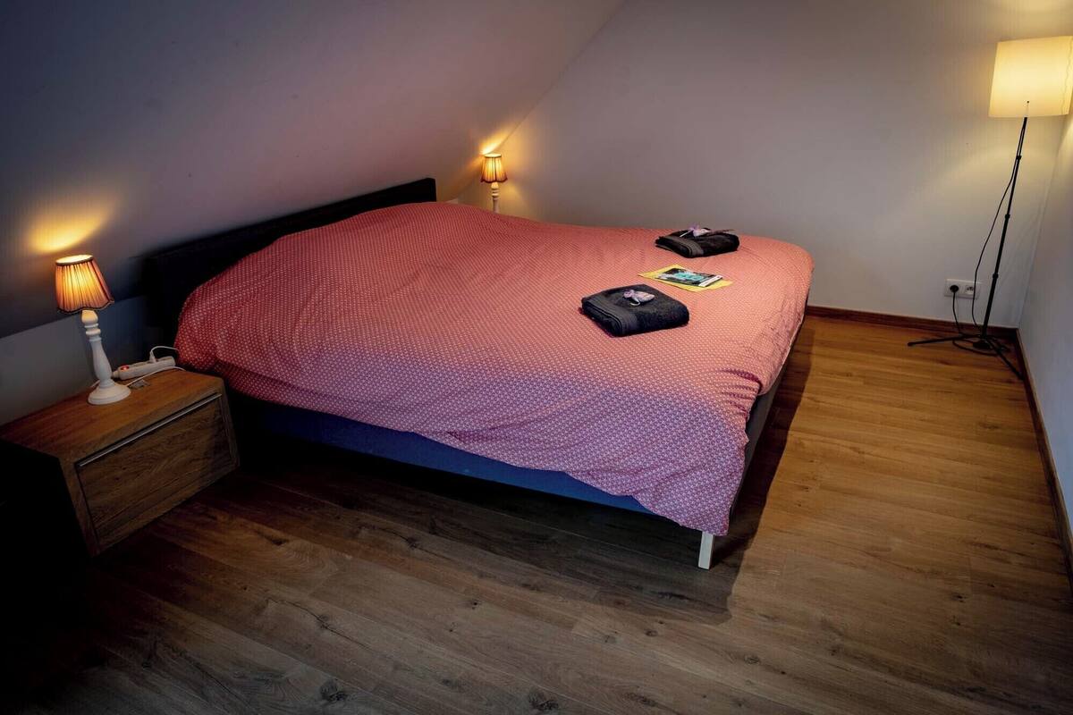 A bedroom with a bed, wooden nightstand, two bedside lamps, and a floor lamp.