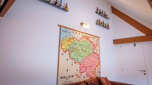 Une carte de la Belgique et des régions avoisinantes est accrochée au mur, et des étagères situées au-dessus servent à exposer des bouteilles.