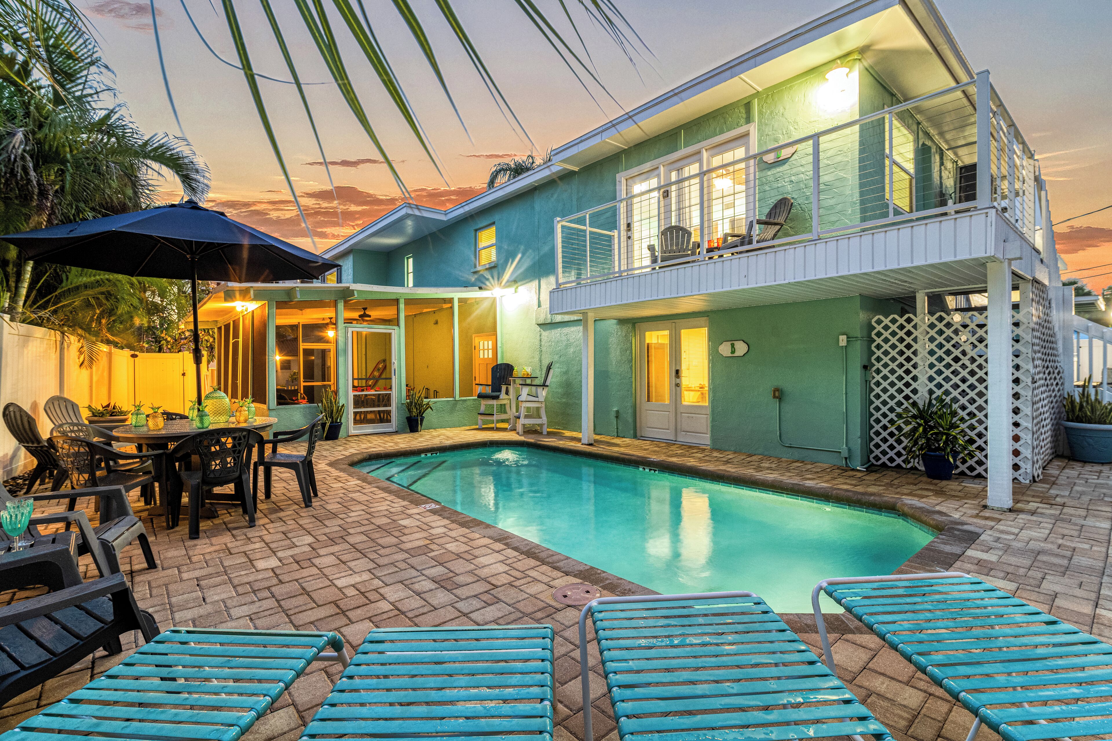 Uma casa de dois andares com piscina, móveis de exterior e um espaço de pátio.