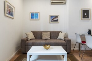 Una sala de estar moderna con un sofá marrón, una mesa de centro blanca y cuadros enmarcados en la pared.