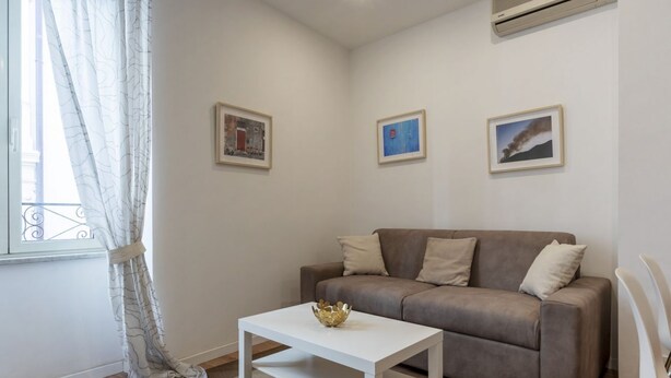A living room with a sofa, a coffee table, and three framed pictures on the wall. - Modern, cozy and comfortable by Fontana di Trevi (Roma)