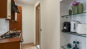 Una cucina compatta con piano cottura a gas, macchina del caffè e frigorifero.
