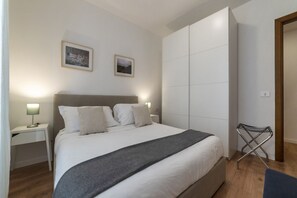 A modern bedroom with a large bed, bedside tables, and a wardrobe.