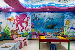 Children can play and explore in this underwater-themed play area with an octopus and sea creatures mural, tables, and chairs.