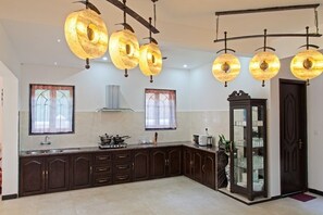 Kitchen features a central island with a stove and various appliances, along with a glass-fronted cabinet displaying kitchenware.