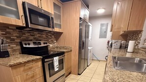 A modern kitchen with wooden cabinets, a stainless steel refrigerator, a microwave, and a stove.